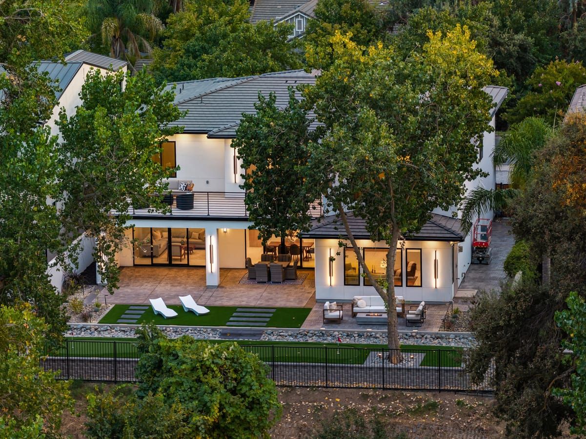 Aerial view of the home at twilight framed by mature trees